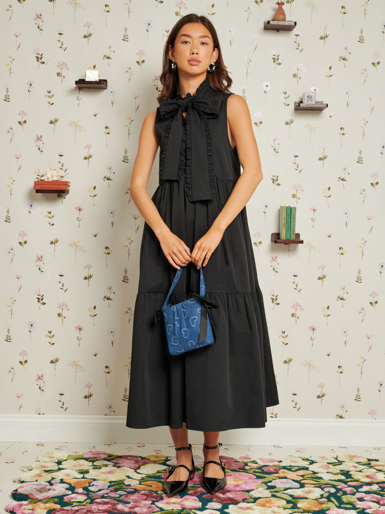 Sister Jane Black Peggy Bow Midi Dress is a loose-fit wonder in lightweight woven fabric designed for any occasion, wherever you may be. This midi dress features a grown-on necktie and side pockets, adding functional grace to the ensemble.